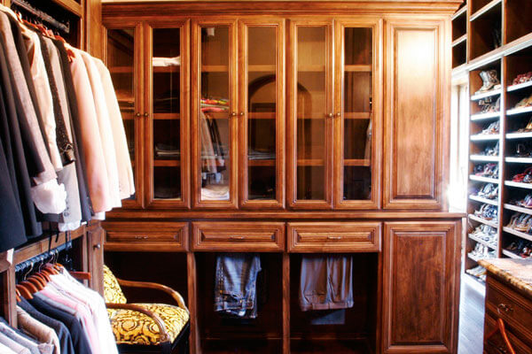Custom built closet organizers with angled shoe racks, glass doors and pull out hanging storage.